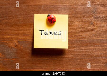 a colored memo sheet with writing  taxes Stock Photo