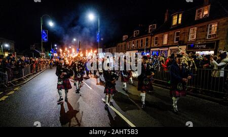 Biggar, Scotland 31st December 2019:  Biggar Pipe Band lead a torchlight procession before the bonfire was set alight. Stock Photo