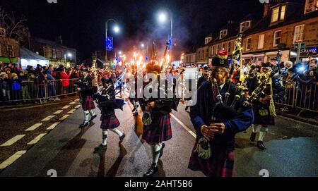 Biggar, Scotland 31st December 2019:  Biggar Pipe Band lead a torchlight procession before the bonfire was set alight.  The Biggar Hogmanay bonfire li Stock Photo