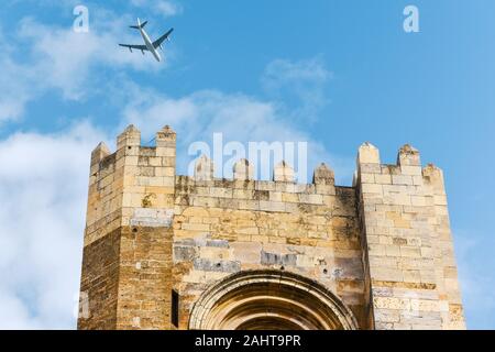 Plane arriving Lisbon flying over the tower of the Lisbon Cathedral. On a sunny day in summer and blue sky. Tourism and travel concept. Lisbon, Portug Stock Photo