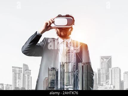 Double exposure of businessman in virtual helmet against cityscape background Stock Photo