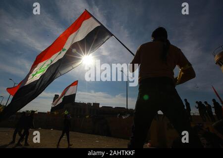 Baghdad, Iraq. 01st Jan, 2020. A protester holds an Iraqi flag during the sit-in in front of the US embassy against deadly US airstrikes on sites of a Shiite militia. Iraqi mourners on Tuesday stormed the building of the US embassy in Baghdad's heavily fortified Green Zone. Credit: Ameer Al Mohmmedaw/dpa/Alamy Live News Stock Photo