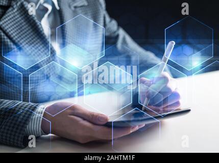 Business and innovation technology concept. Virtual geometric graphics with hexagons. Businessman working at tablet computer. Double exposure image wi Stock Photo