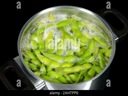 Edamame, green soybeans, maodou, boiling in saltwater in a metal pot. Soy beans, Glycine max., a legume that bis rich on protein. Stock Photo