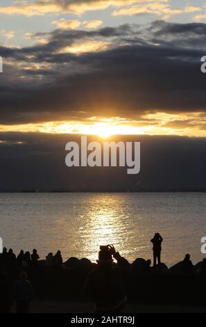 Tokyo, Japan. 1st Jan, 2020. People watch the sunrise which appears behind the clouds on the New Year's Day at a beach in Tokyo on Wednesday, January 1, 2020. Millions of Japanese people visit shrines and temples to celebrate the New Year. Credit: Yoshio Tsunoda/AFLO/Alamy Live News Stock Photo