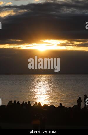 Tokyo, Japan. 1st Jan, 2020. People watch the sunrise which appears behind the clouds on the New Year's Day at a beach in Tokyo on Wednesday, January 1, 2020. Millions of Japanese people visit shrines and temples to celebrate the New Year. Credit: Yoshio Tsunoda/AFLO/Alamy Live News Stock Photo