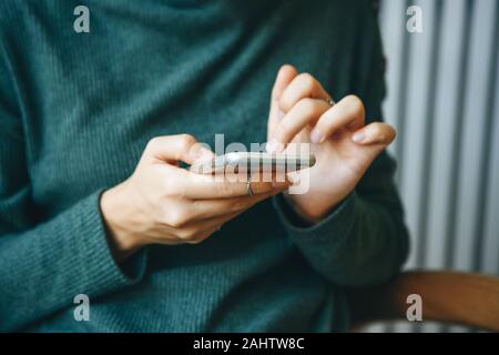 Closeup girl uses a cellphone. Hands with a mobile phone. Modern technology in everyday life. Stock Photo