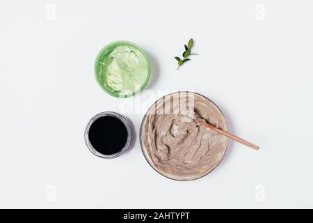 Top view natural cosmetics clay mask, activated charcoal powder and aloe gel on white table, flat lay Stock Photo