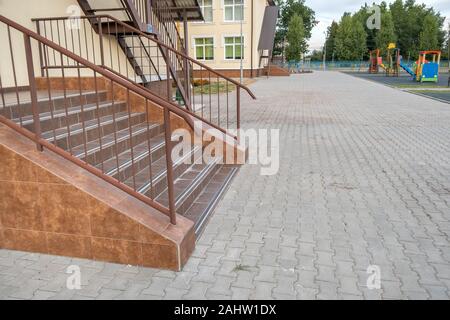 Concrete entrance stairs covered with ceramic tiles with metal railings outdoors. Stock Photo