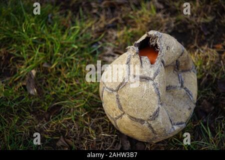 Torn soccer ball lies on the old green grass. Stock Photo