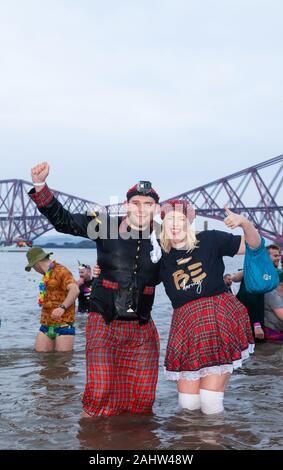 South Queensferry, Edinburgh, Scotland. 1st Jan 2020..  Revellers braving the cold water for the Traditional New Years Day Loony Dook with the Iconic Forth Bridge in the Background Credit: Richard Newton/Alamy Live News Stock Photo