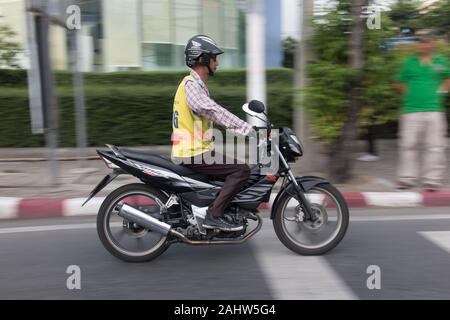 SAMUT PRAKAN, THAILAND, JUN 03 2019, A man with yellow vest of taxi ride on a  motorbike. Motorcycle with taxi driver with helmet on city street. Stock Photo