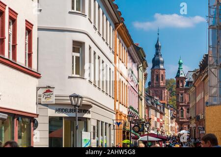 Nice street level view of the main street with shops and restaurants in Heidelberg and the tower of the Church of the Holy Spirit (Heiliggeistkirche)... Stock Photo