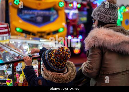 A mother and child playing coin push machines in an amusement arcade Stock Photo
