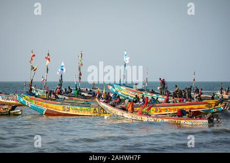 TANJI, THE GAMBIA - NOVEMBER 21, 2019: Scene with men and women carrying fish from the boats to the beach on Tanji, Gambia, West Africa. Stock Photo