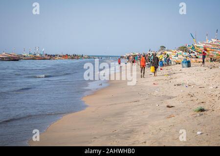 TANJI, THE GAMBIA - NOVEMBER 21, 2019: Scene with men and women carrying fish from the boats to the beach on Tanji, Gambia, West Africa. Stock Photo