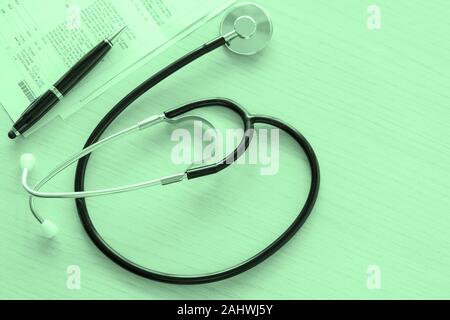 Stethoscope and medical documents on doctor table on green background, close-up and view directly above. Medical examination, health care concept. Stock Photo