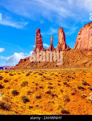 Towering red sandstone formations of the Three Sisters Pinnacles and Mitchell Mesa in Monument Valley Navajo Tribal Park desert landscape in AZ -UT Stock Photo