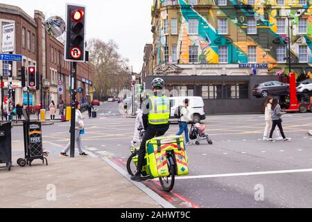 London ambulance paramedic on a bicycle waiting at a traffic light, kings cross, london, uk Stock Photo