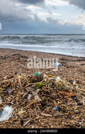 Spilled garbage on the beach of the big city. Empty used dirty plastic bottles. Dirty sea sandy shore. Environmental pollution. Ecological problem. Bo Stock Photo