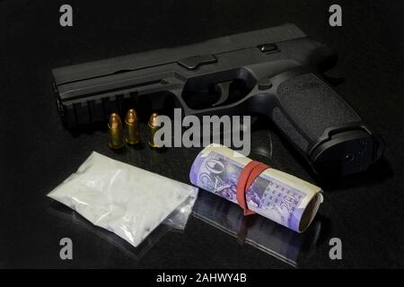 Bag of powdered drugs with a Sig Sauer handgun and a roll of  £20 pound notes (GBP)  on a black background. Stock Photo