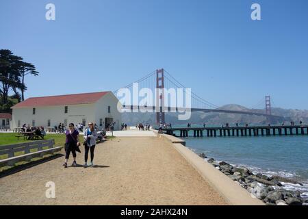 Crissy Field in the Presidio, the  Warming Hut store and cafe, the Golden Gate Bridge, and people fishing on Torpedo wharf Stock Photo
