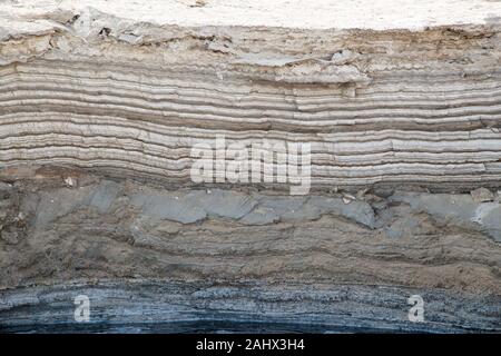 Annual layers of salt and minerals deposited on the shore of the Dead Sea in Israel and exposed by dropping water levels. Stock Photo