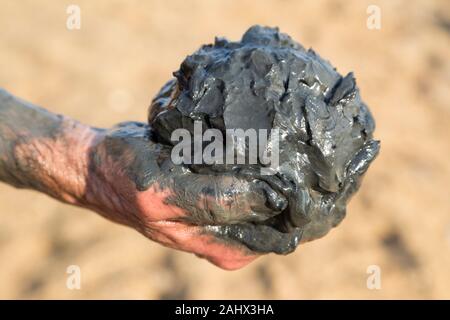 Tourist holding a handful of Dead Sea mud picked up from the beach Stock Photo