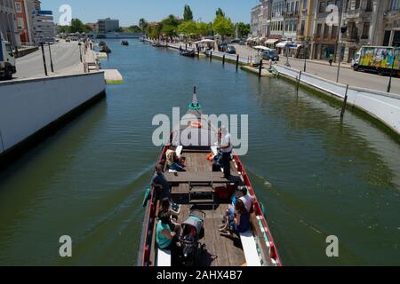 Tourists enjoy a boat trip on a traditional Moliceiro canal boat on the central canal in Aveiro Portugal Stock Photo