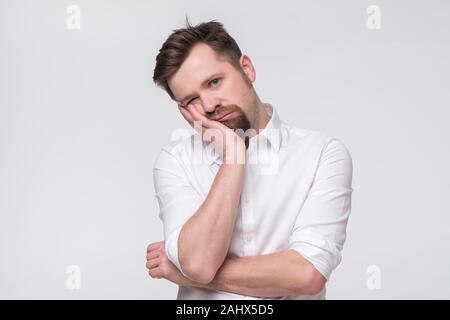 Bored mature caucasian man with beard holding hand on cheek looking tired and sick Stock Photo