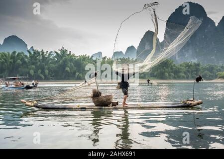Fisherman throwing a cast net high in the air, Li River near Xingping, Guangxi Province, China Stock Photo