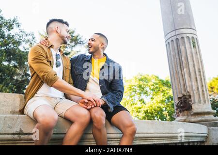 Portrait of happy gay couple spending time together and having a date at the park. Lgbt and love concept.