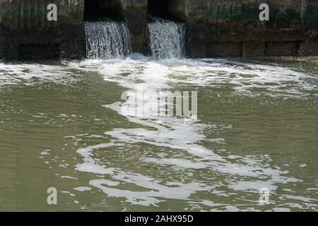Dirty water flows from a pipe,Sewage pipe polluting water Stock Photo