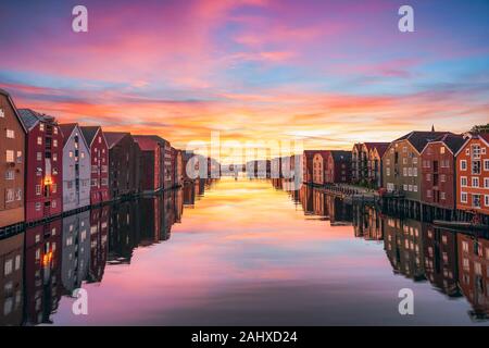 View of colorful timber houses surrounding river Nidelva in the city of Trondheim at sunset. View from Old Town Bridge. Trondelag county. Norway Stock Photo