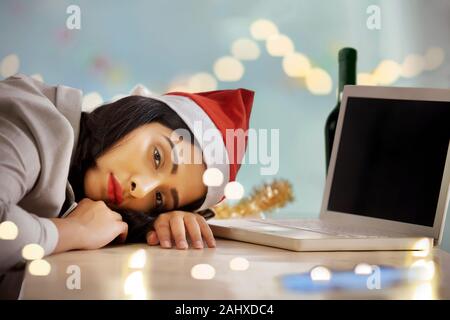 Young woman in office lying in front of her laptop during new years party. Stock Photo