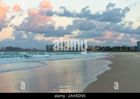 Beach view with soft waves and urban cityscape at sunset. Coolangatta, Australia