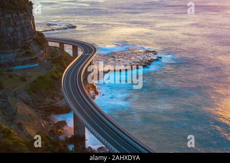Aerial view of bridge along cliff edge and ocean. Sea Cliff Bridge view on sunrise. Illawarra, New South Wales, Australia