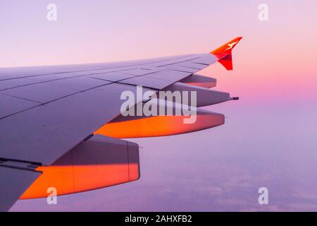 View of the starboard wing of a Qantas Airbus A380 airliner approaching Sydney Airport at sunrise, Australia Stock Photo