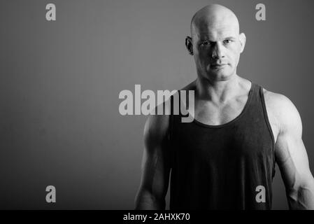 Bald muscular man wearing tank top against gray background Stock Photo