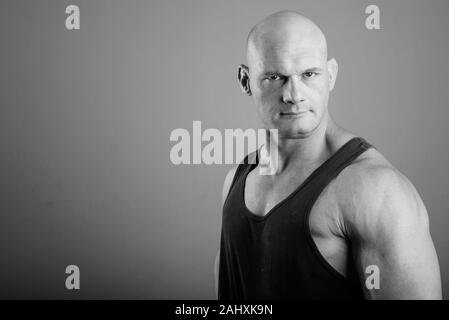 Bald muscular man wearing tank top against gray background Stock Photo