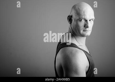 Bald muscular man wearing tank top against gray background Stock Photo