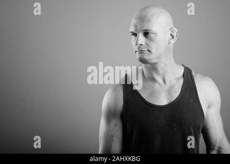 Bald muscular man wearing tank top against gray background Stock Photo