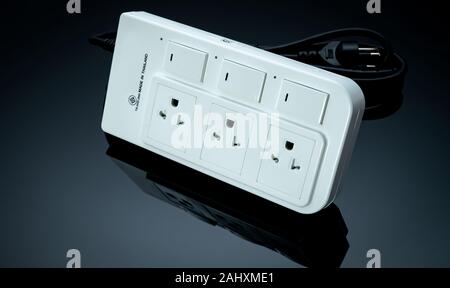Power strip with three electrical standard socket on black background. White universal plug with overload protection. Fire resistant material for cove Stock Photo