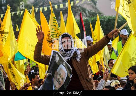 January 1, 2020: Gaza, Palestine. 01 January 2020. Supporters of the Palestinian Fatah movement take part in a rally in Gaza City to celebrate the 55th foundation anniversary of the political party. Participants waved the yellow party flags and displayed the portrait of Fatah chairman and Palestinian Authority President Mahmoud Abbas, of Fatah's founder and previous chairman Yasser Arafat, as well as of Marwan Barghouti, a Palestinian political figure imprisoned by Israel. A big torch with the Fatah logo was lit during the event. The Palestinian Fatah movement, previosly known as the Palesti Stock Photo