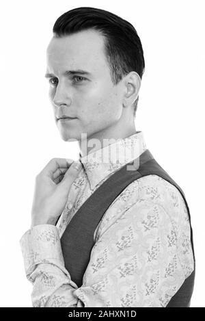 Studio shot of young handsome businessman thinking while fixing collar Stock Photo