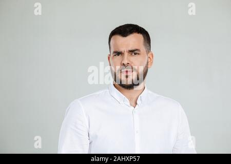 Portrait of young frowned handsome bearded man on gray background. facial expression Stock Photo