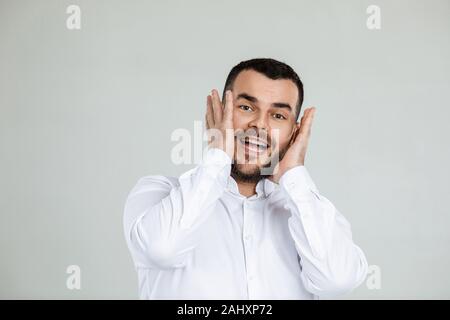 Portrait of young surprised handsome bearded man with shocked facial expression on gray background Stock Photo