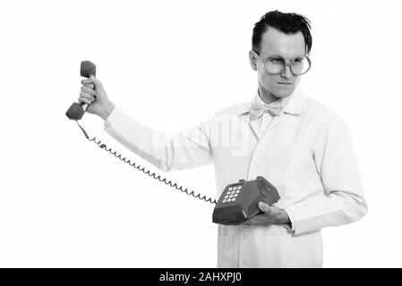 Studio shot of young crazy man doctor holding old telephone and looking angry Stock Photo