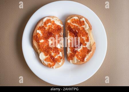 A two sandwiches with butter and red caviar on a white plate, top view Stock Photo