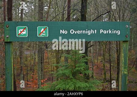 No overnight parking sign with forest background with crossed out symbols for caravans and fires. Taken at Loch Dunmore, Perthshire, Scotland. Stock Photo